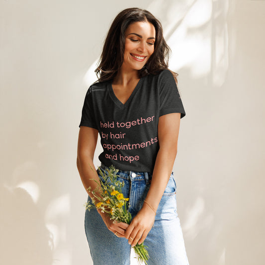 It Girl x Arté "Held Together By Hair Appointments And Hope" V-Neck Tee in black, cheeky phrase in It Girl Wellness pink across the back